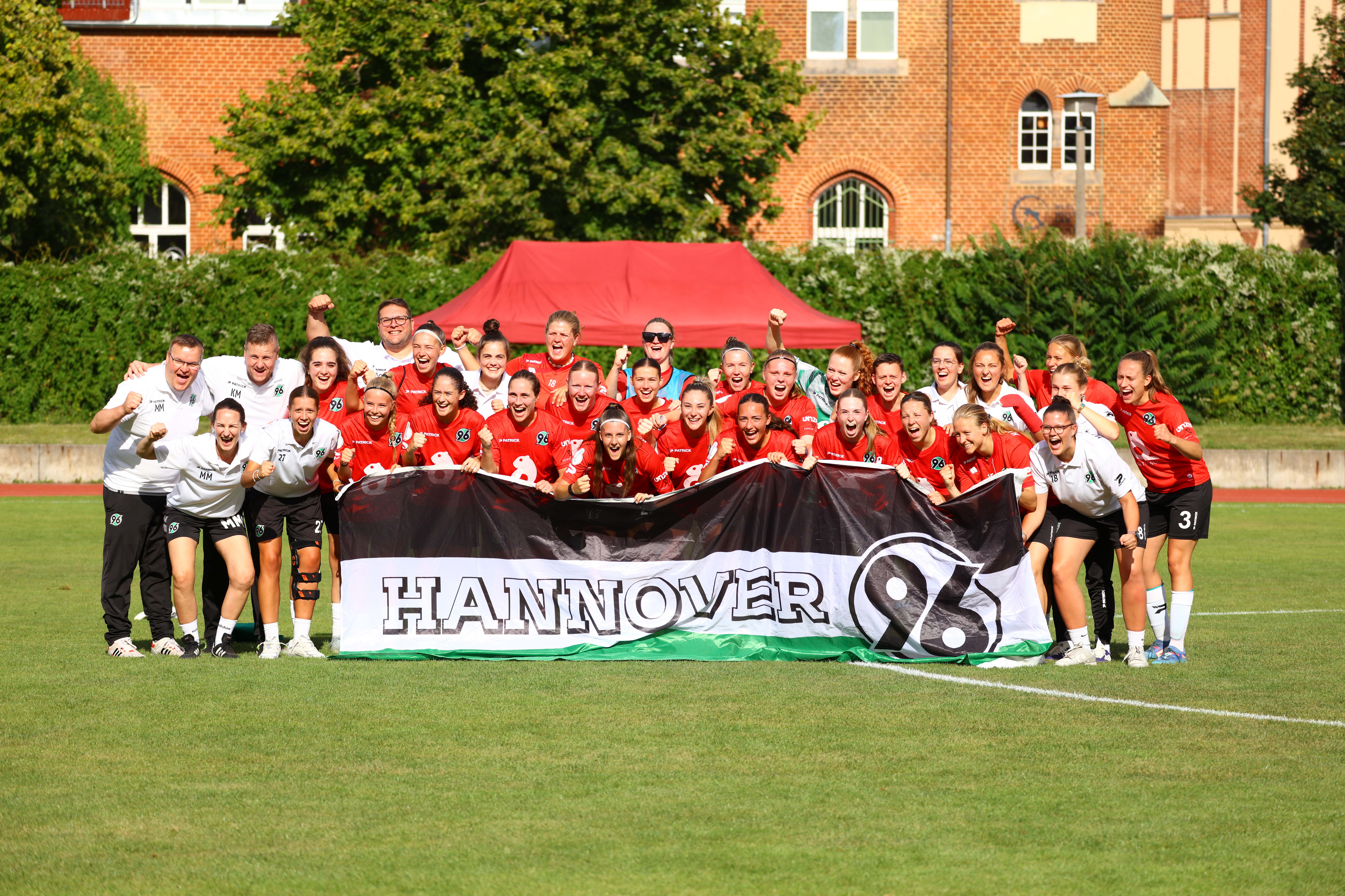Ein Mannschaftsbild der ersten Frauenmannschaft, die eine Flagge von Hannover 96 in die Kamera halten.