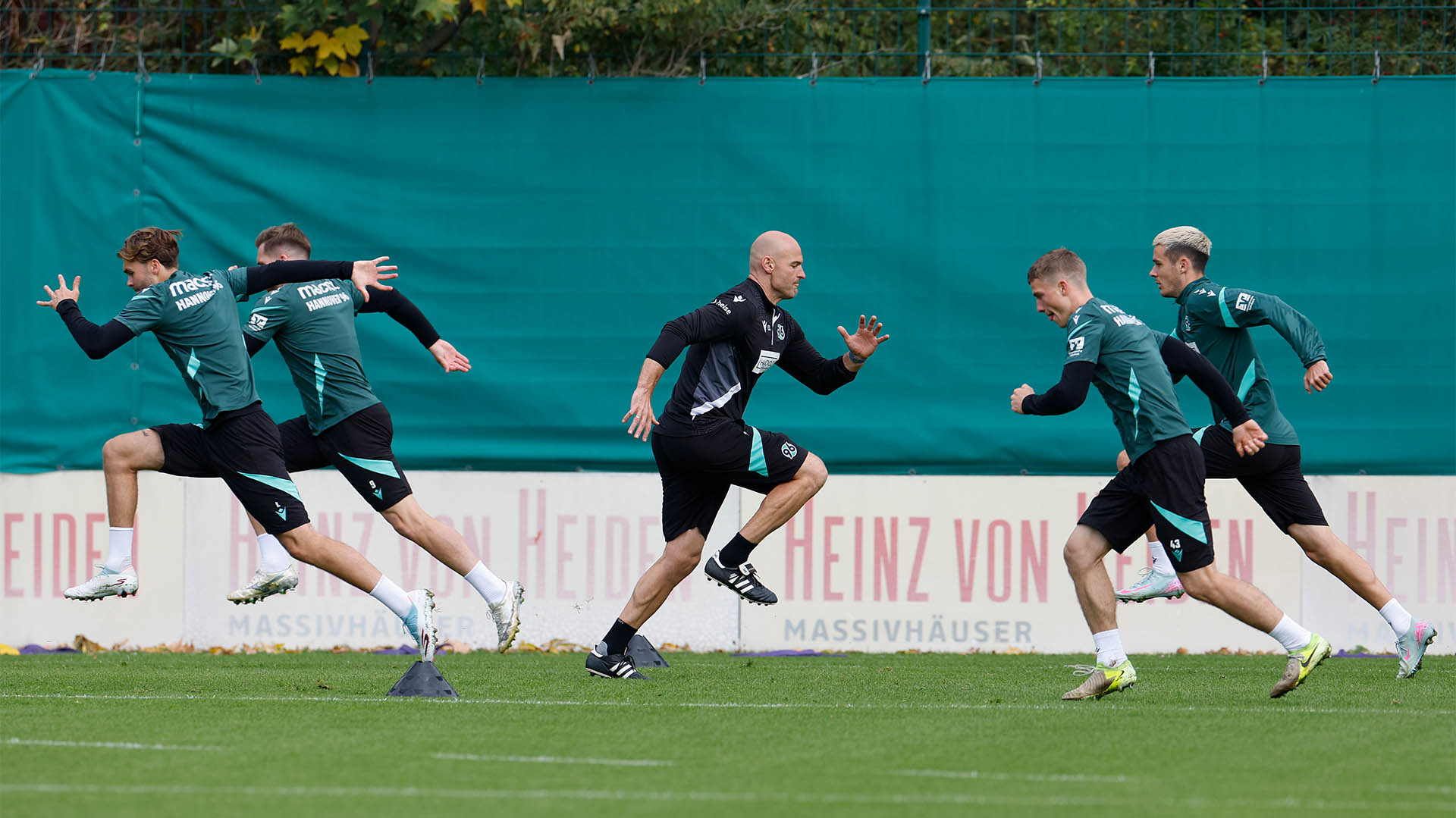 Athletiktrainer Felix Sunke in der Mitte, rechts und links von ihm jeweils zwei Spieler, die mit großen Schritten laufen.