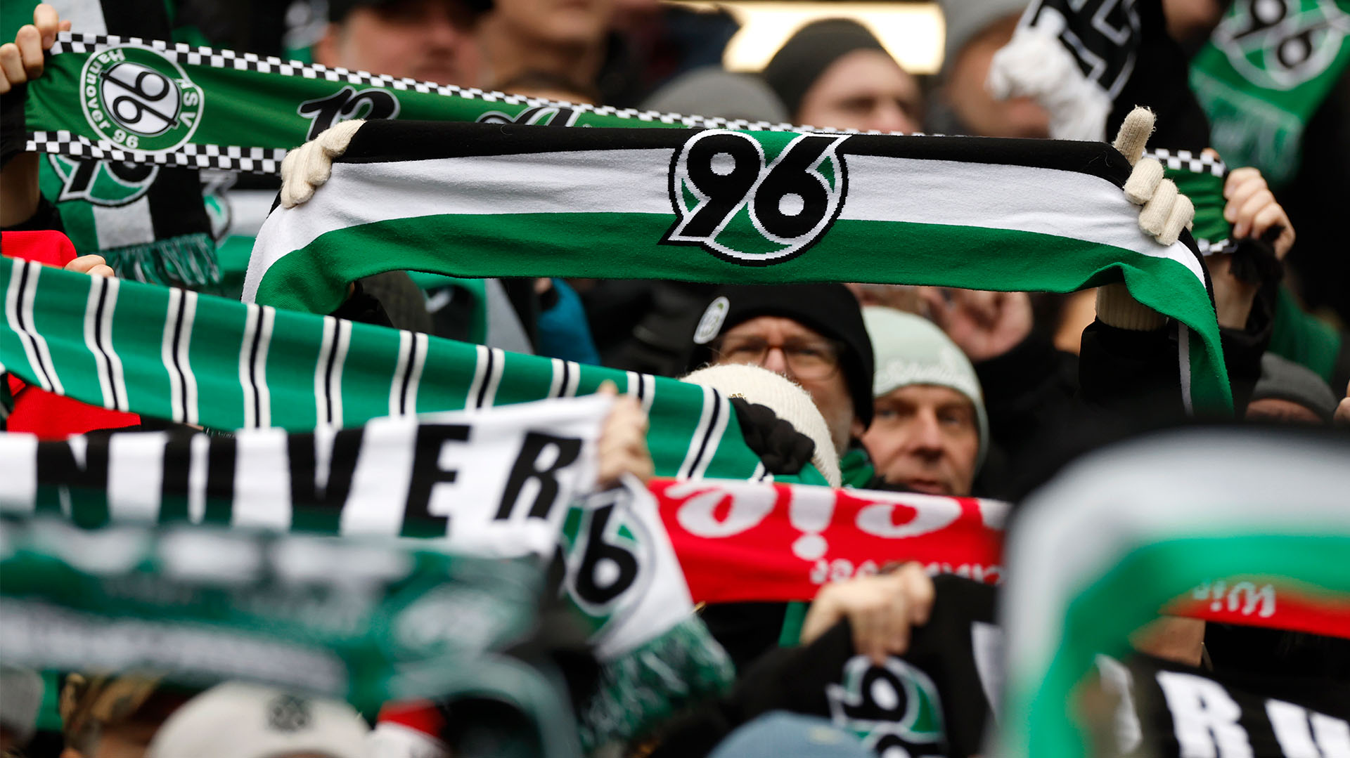 96-Schals werden in die Höhe gehalten, Gesichter sind nicht zu erkennen.