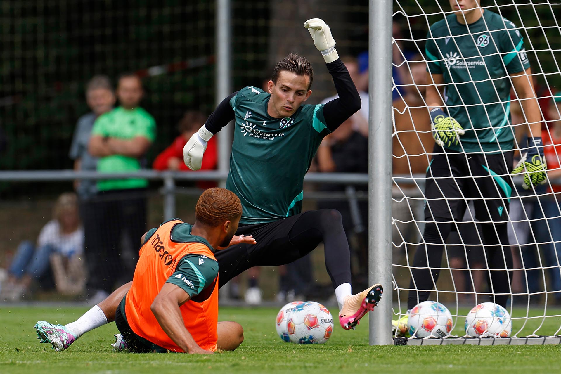  Hannover-96-Torhüter Nahuel Noll pariert einen Ball mit dem linken Fuß, Brooklyn Ezeh rutscht fast in ihn herein.
