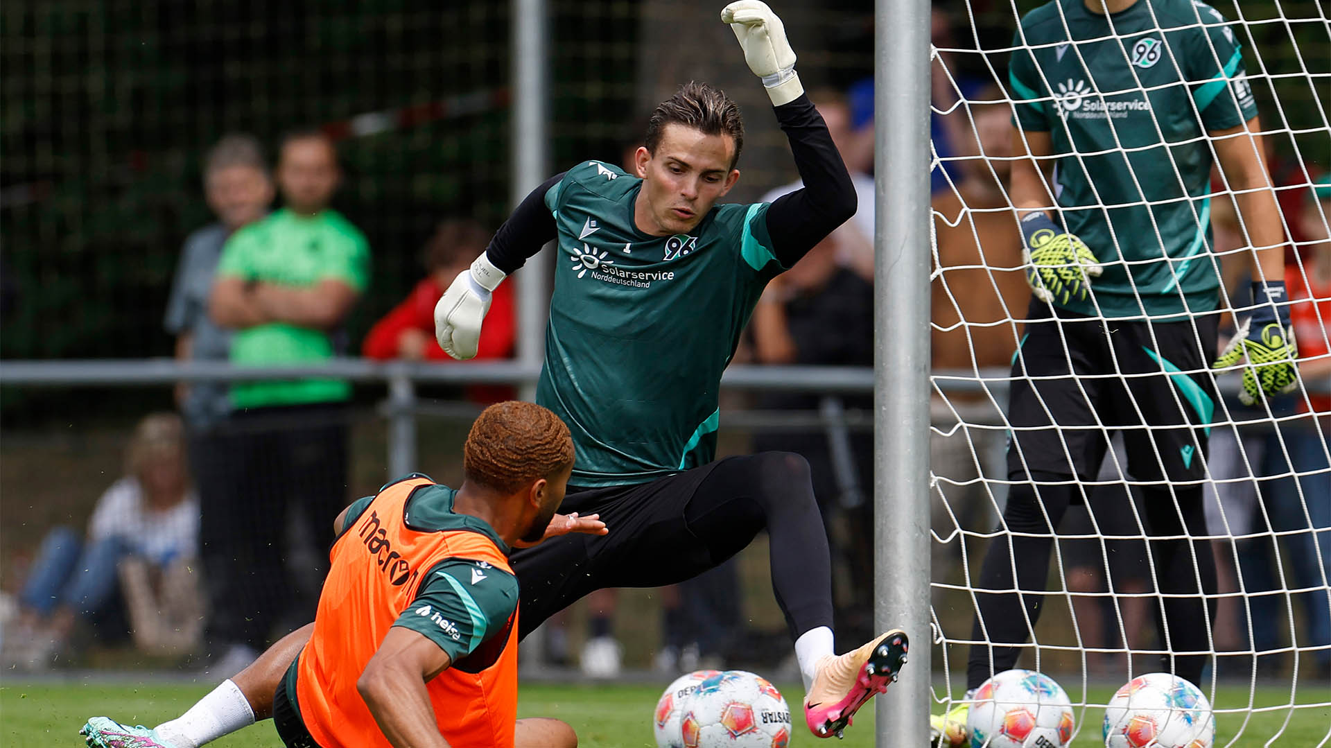  Hannover-96-Torhüter Nahuel Noll pariert einen Ball mit dem linken Fuß, Brooklyn Ezeh rutscht fast in ihn herein.
