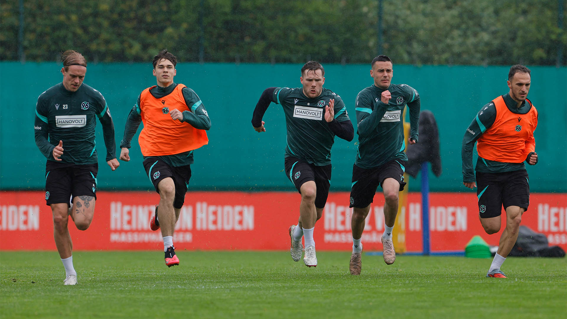 Fünf Spieler sprinten auf dem Trainingsplatz im Regen.