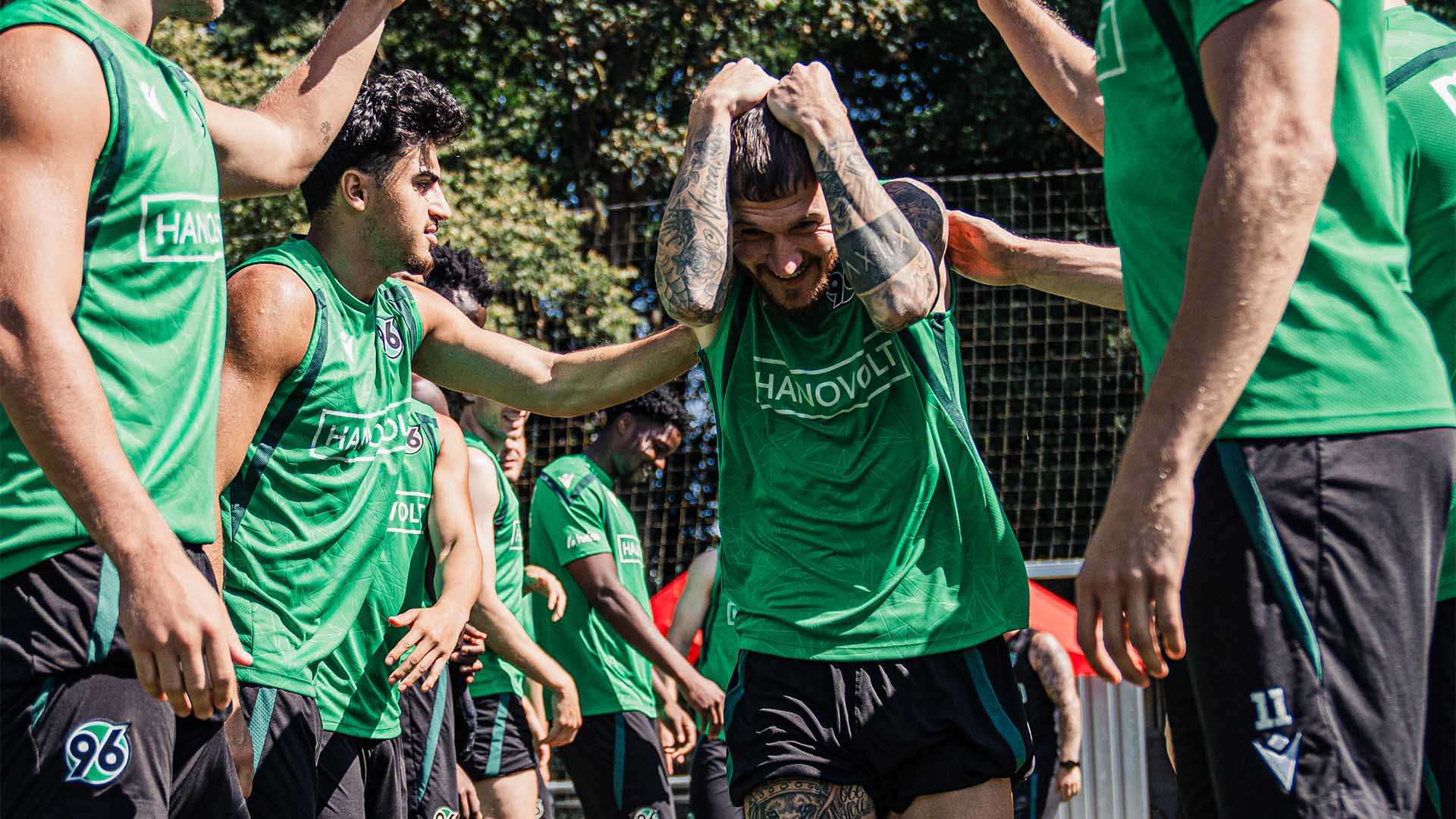Der 96-Spieler Marcel Hartel läuft auf dem Trainingsplatz durch ein Spalier von anderen Spielern und hält sich die Hände über den Kopf.