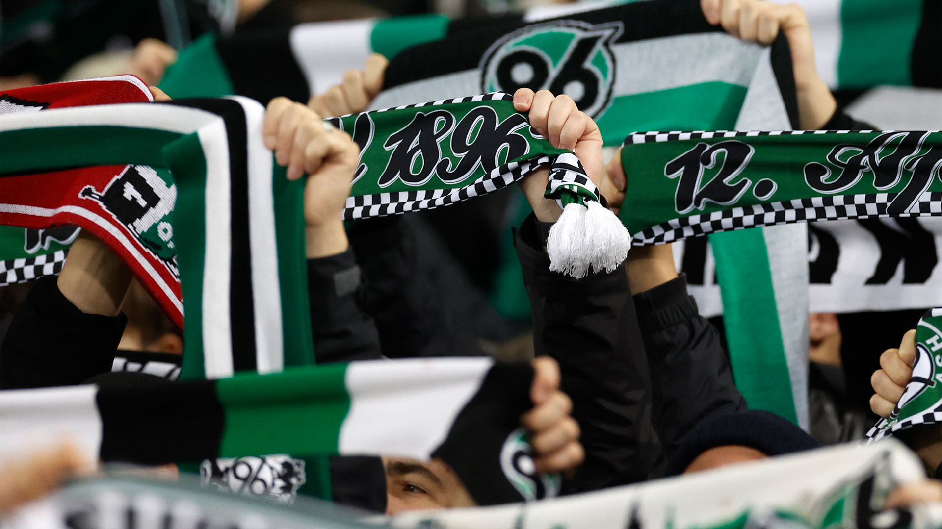 96-Schals werden hochgehalten, Gesichter sind nicht zu erkennen.