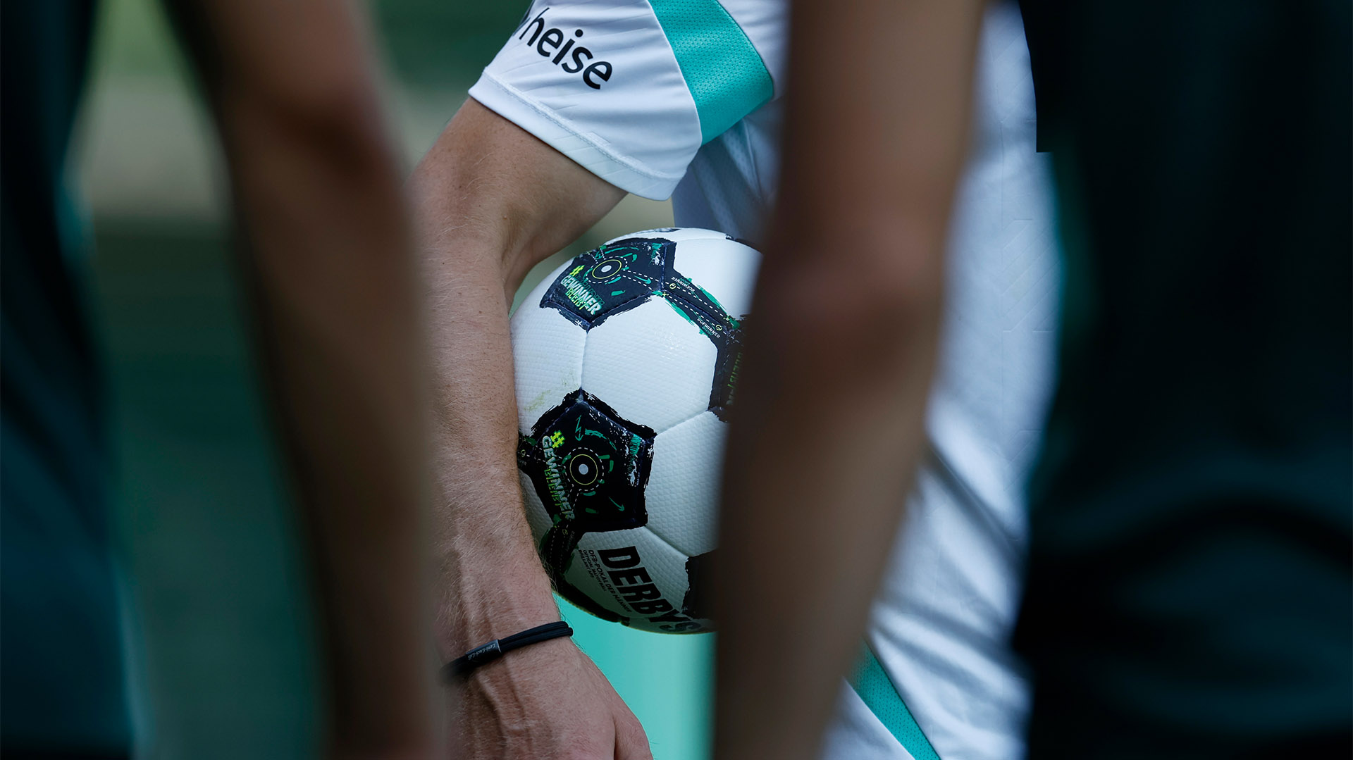 Der Oberkörper einer Person, die einen DFB-Pokalball hält, ist zu sehen. 