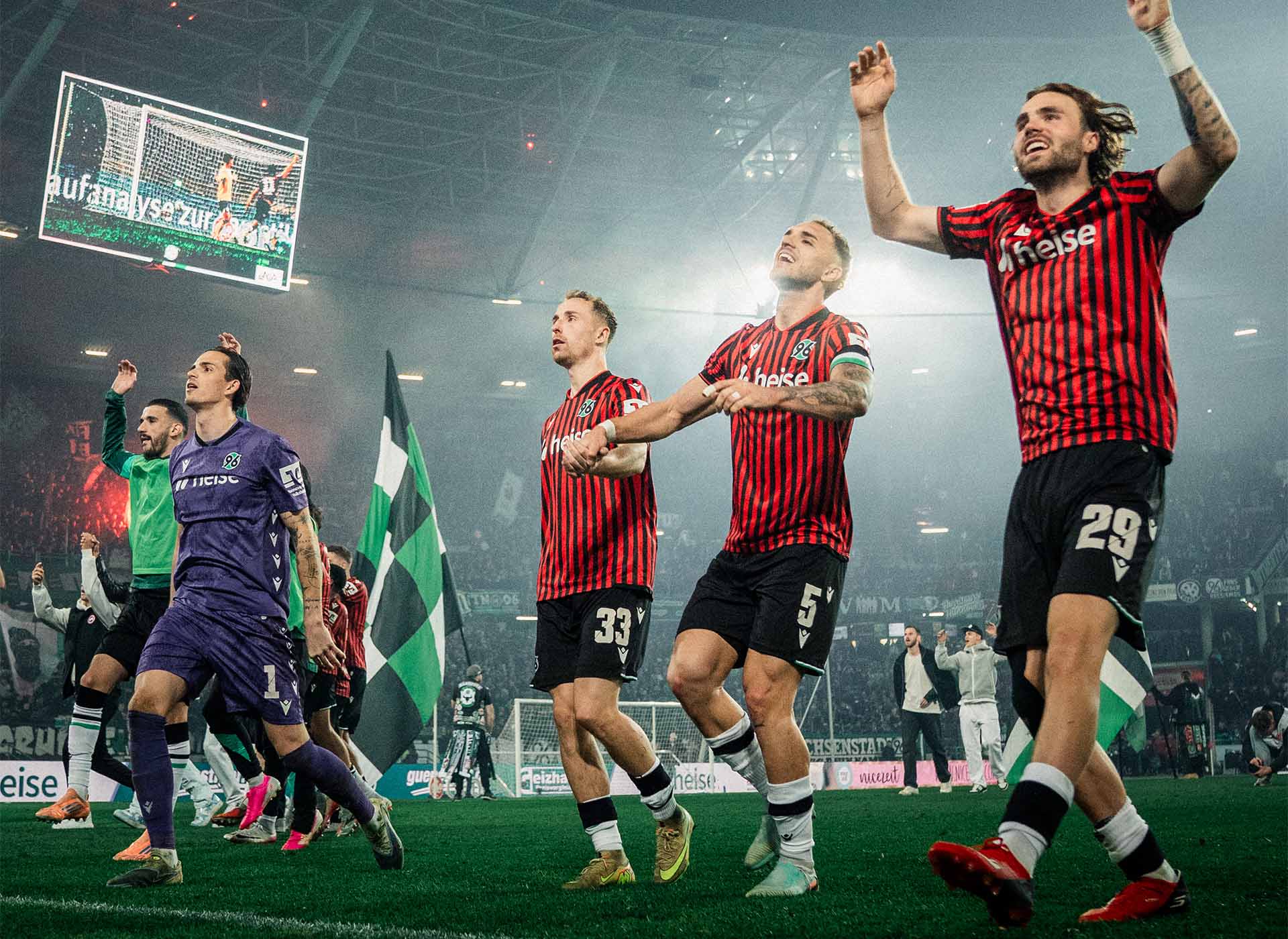 Die 96-Spieler springen Hand in Hand hoch, im Hintergrund das dunkle Stadion.