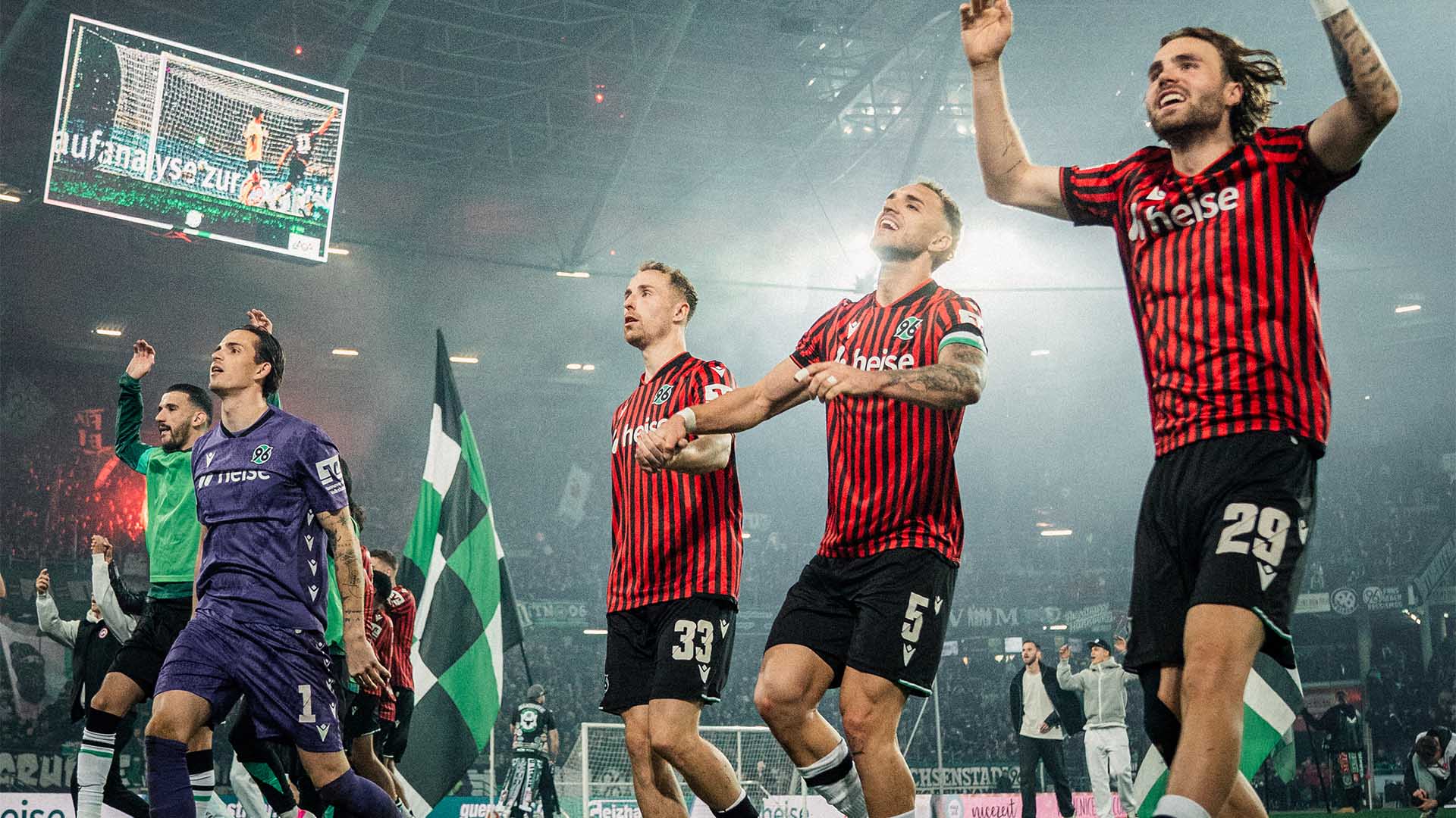 Die 96-Spieler springen Hand in Hand hoch, im Hintergrund das dunkle Stadion.