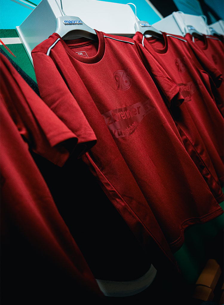 Dunkelrote Shirts hängen an Bügeln in einer Reihe.