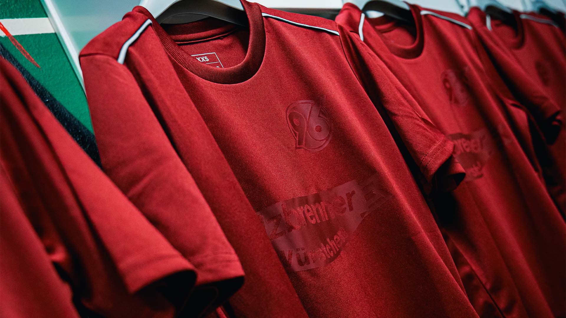 Dunkelrote Shirts hängen an Bügeln in einer Reihe.