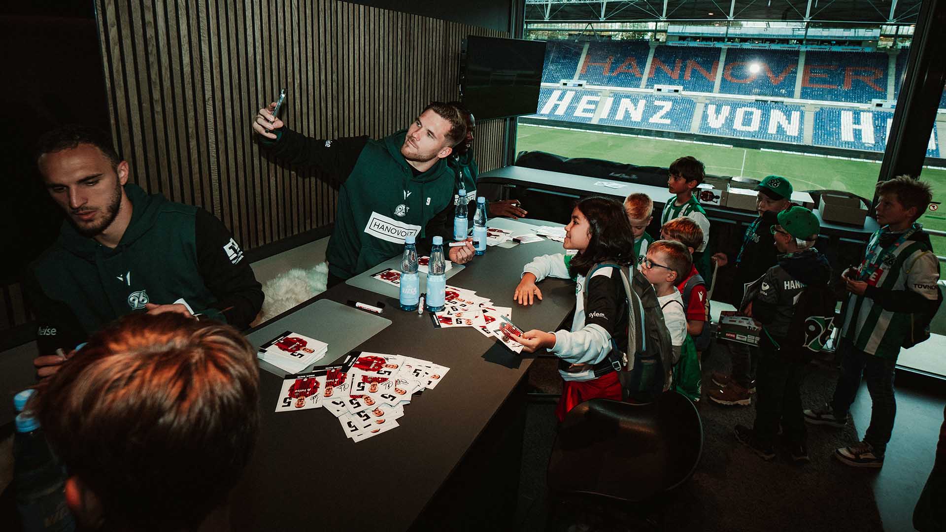 Virgil Ghita, Benjamin Källman und Mustapha Bunde schreiben Autogramme in einer Loge, Källman macht ein Selfie mit einigen Kids.
