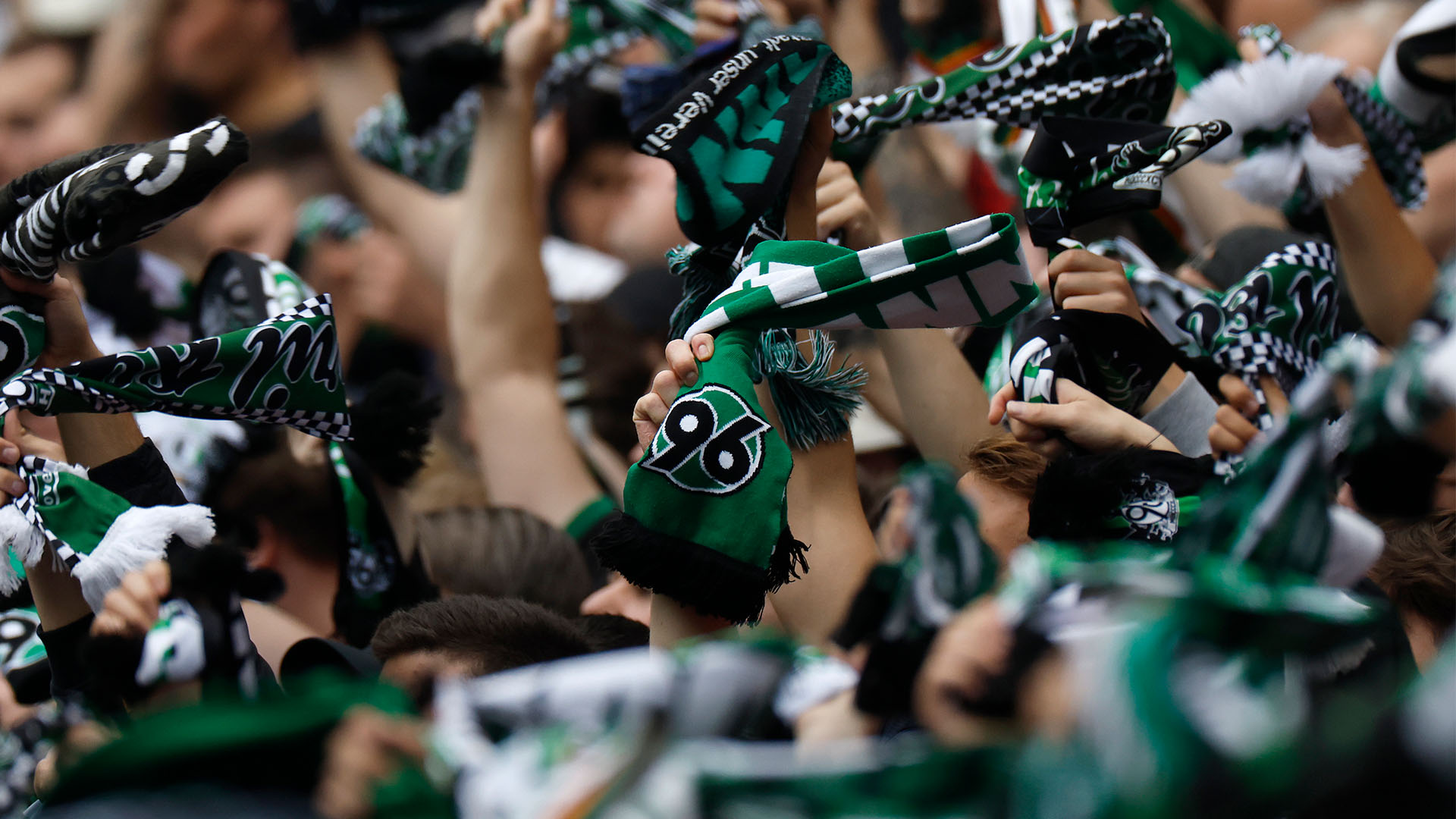 96-Fans schwenken Schals, Gesichter sind nicht zu erkennen.