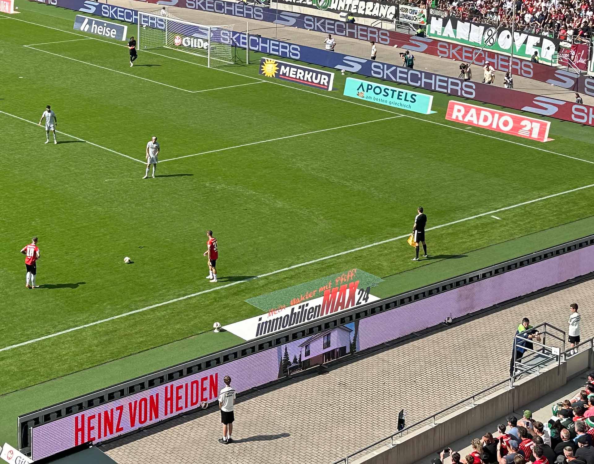 Blick in die Heinz von Heiden Arena bei einem Spiel, im Zentrum des Bildes liegt ein Cam Carpet mit ImmobilienMAX24-Logo.
