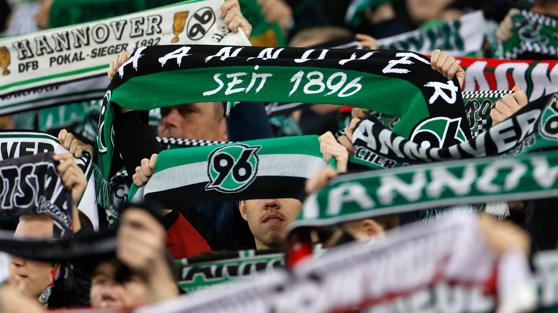 96-Schals werden hochgehalten, Personen sind nicht zu erkennen.