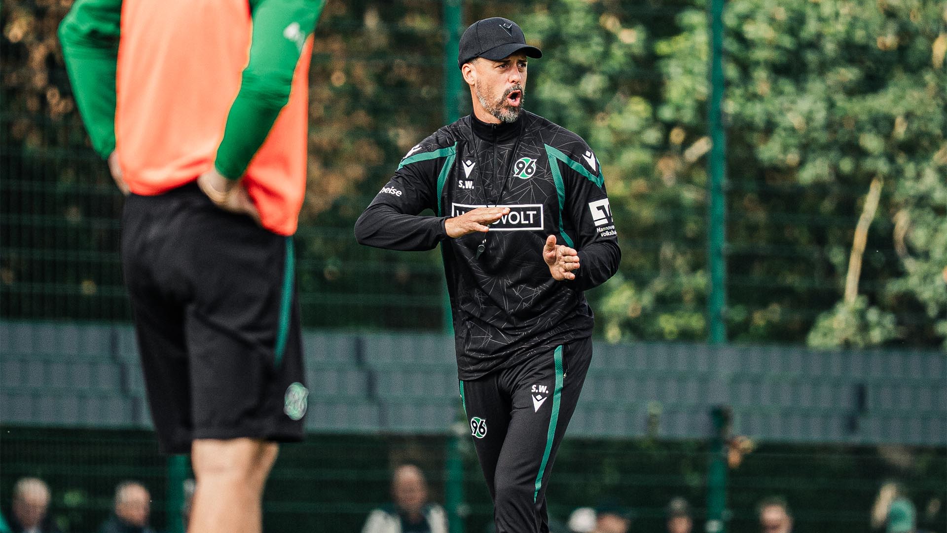 Der 96-Trainer Sandro Wagner steht auf dem Trainingsplatz, sagt etwas an und gestikuliert dabei mit den Händen.