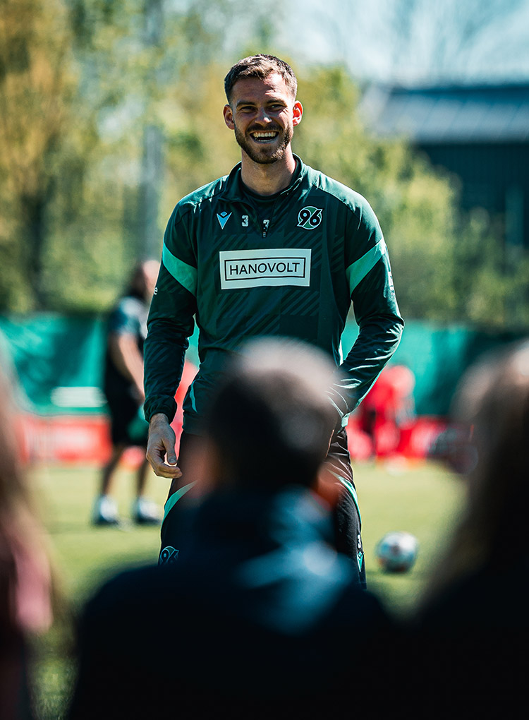 Boris Tomiak strahlt bei Sonnenschein beim Training, im Vordergrund unscharf Zuschauer.