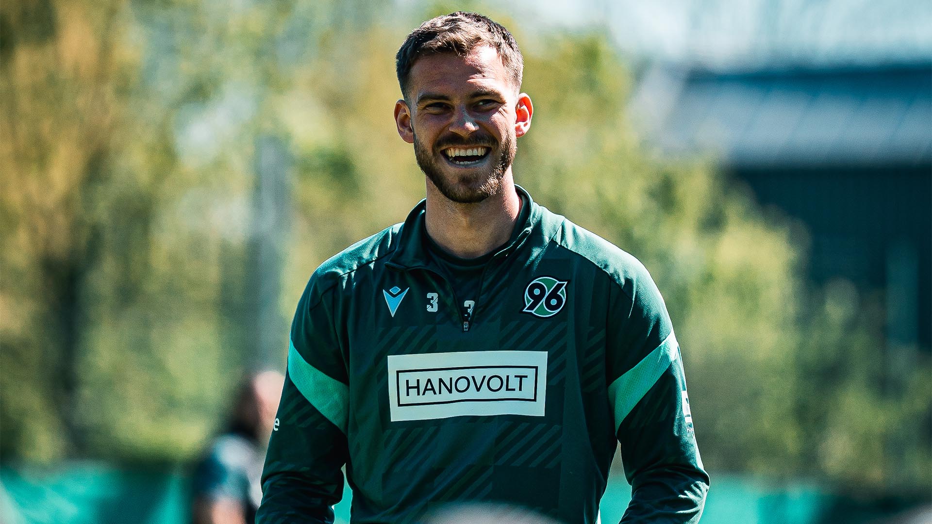 Boris Tomiak strahlt bei Sonnenschein beim Training, im Vordergrund unscharf Zuschauer.