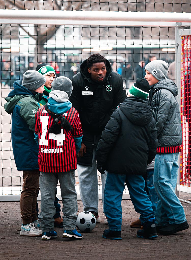 Im Okeon spricht mit fünf Kindern, die im Halbkreis vor ihm stehen. Alle sind dick angezogen.