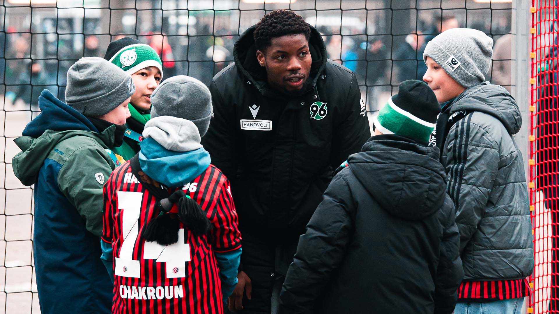 Im Okeon spricht mit fünf Kindern, die im Halbkreis vor ihm stehen. Alle sind dick angezogen.