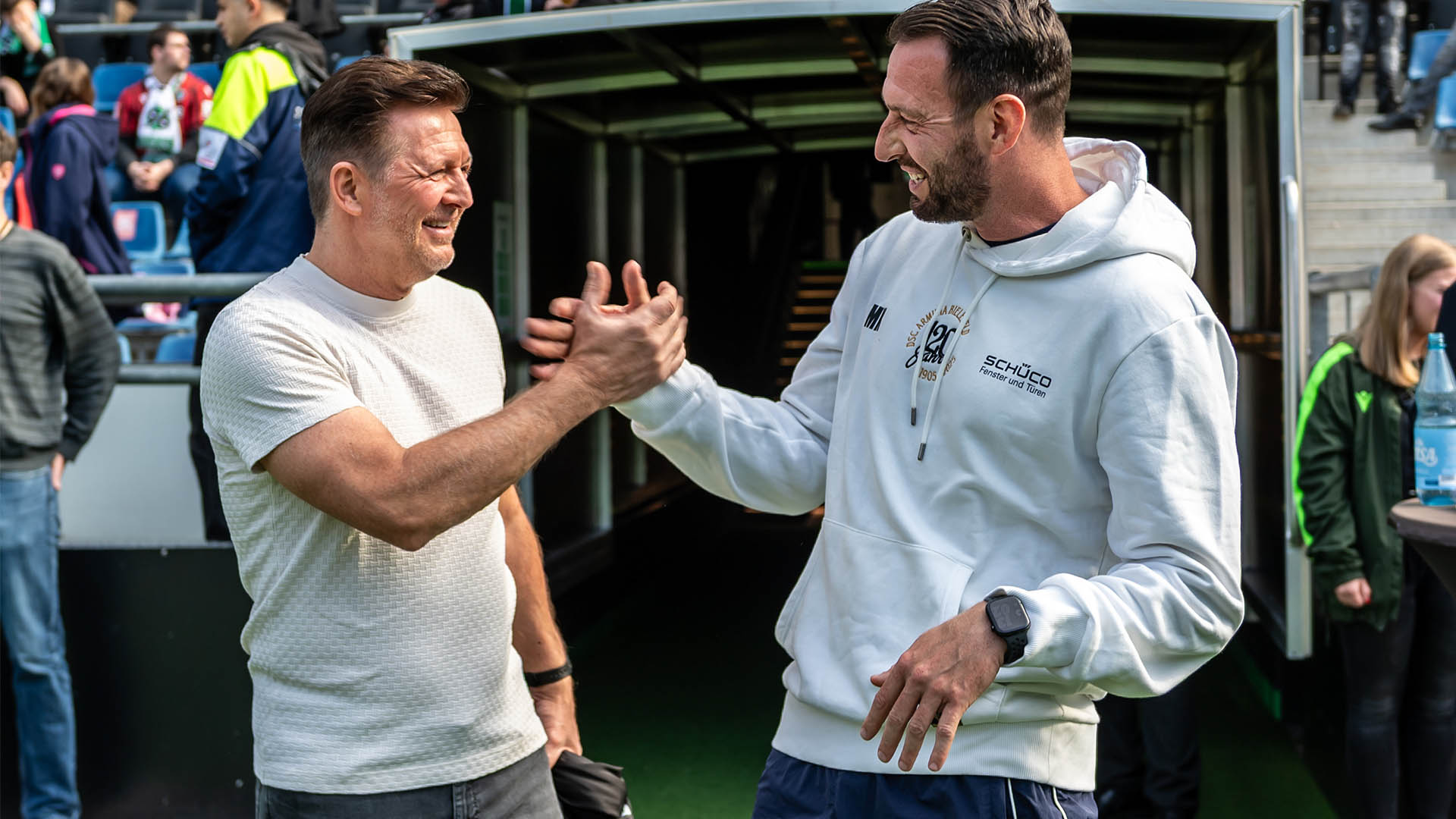 Christian Titz und Mitch Kniat schlagen ein und lachen dabei.