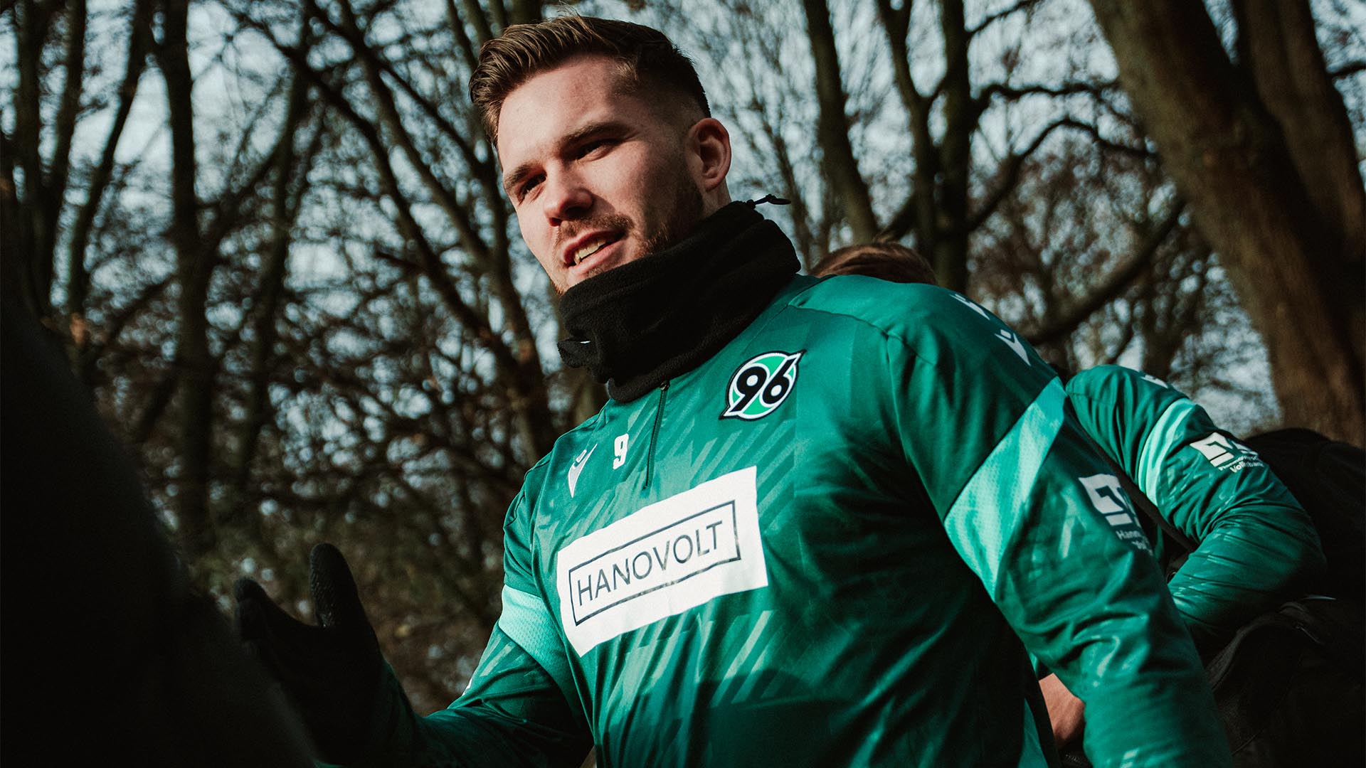 Benjamin Källman betritt den Trainingsplatz und schlägt mit jemandem, der nicht im Bild ist, ein.
