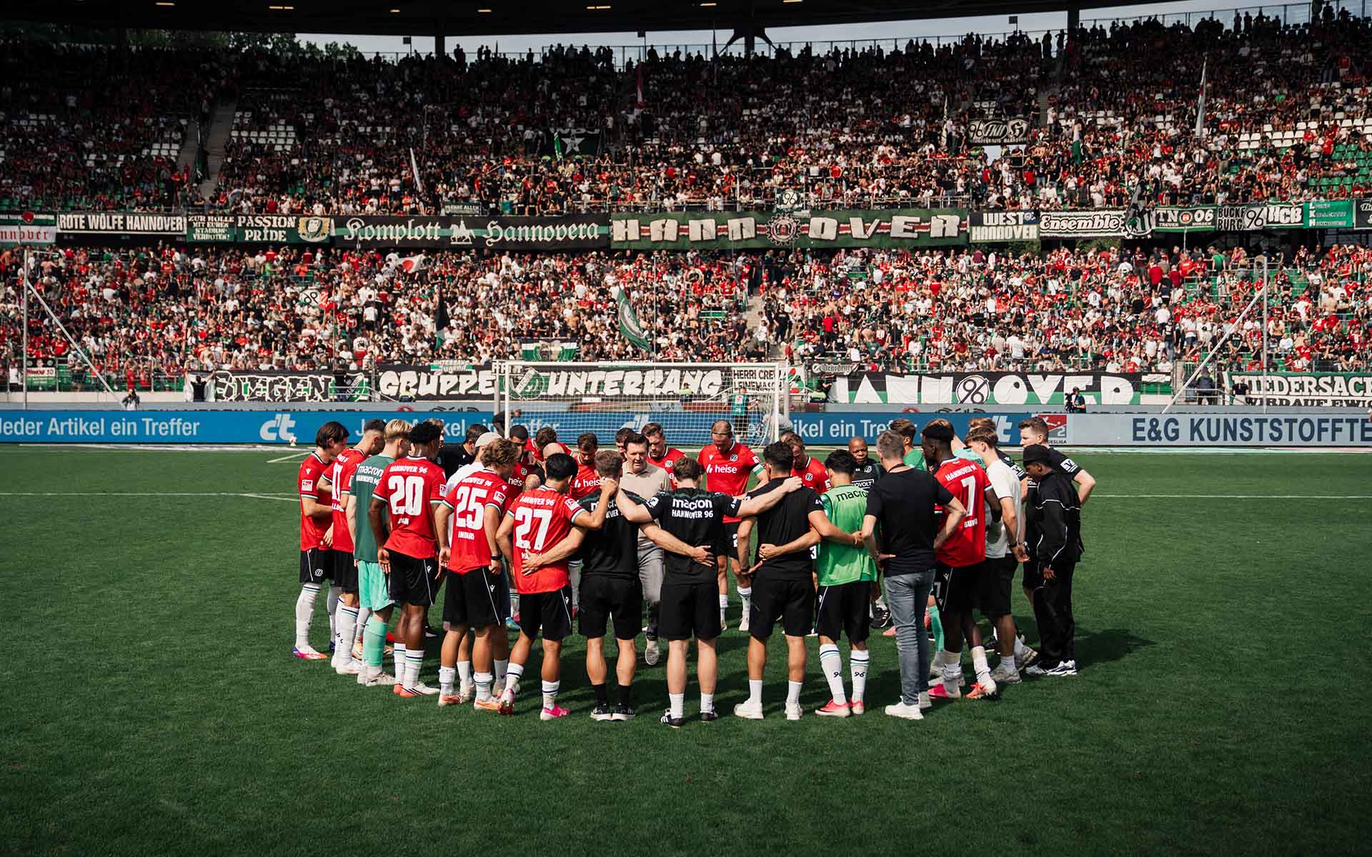 Die komplette 96-Mannschaft bildet einen Kreis vor der vollen Nordkurve im 96-Stadion.