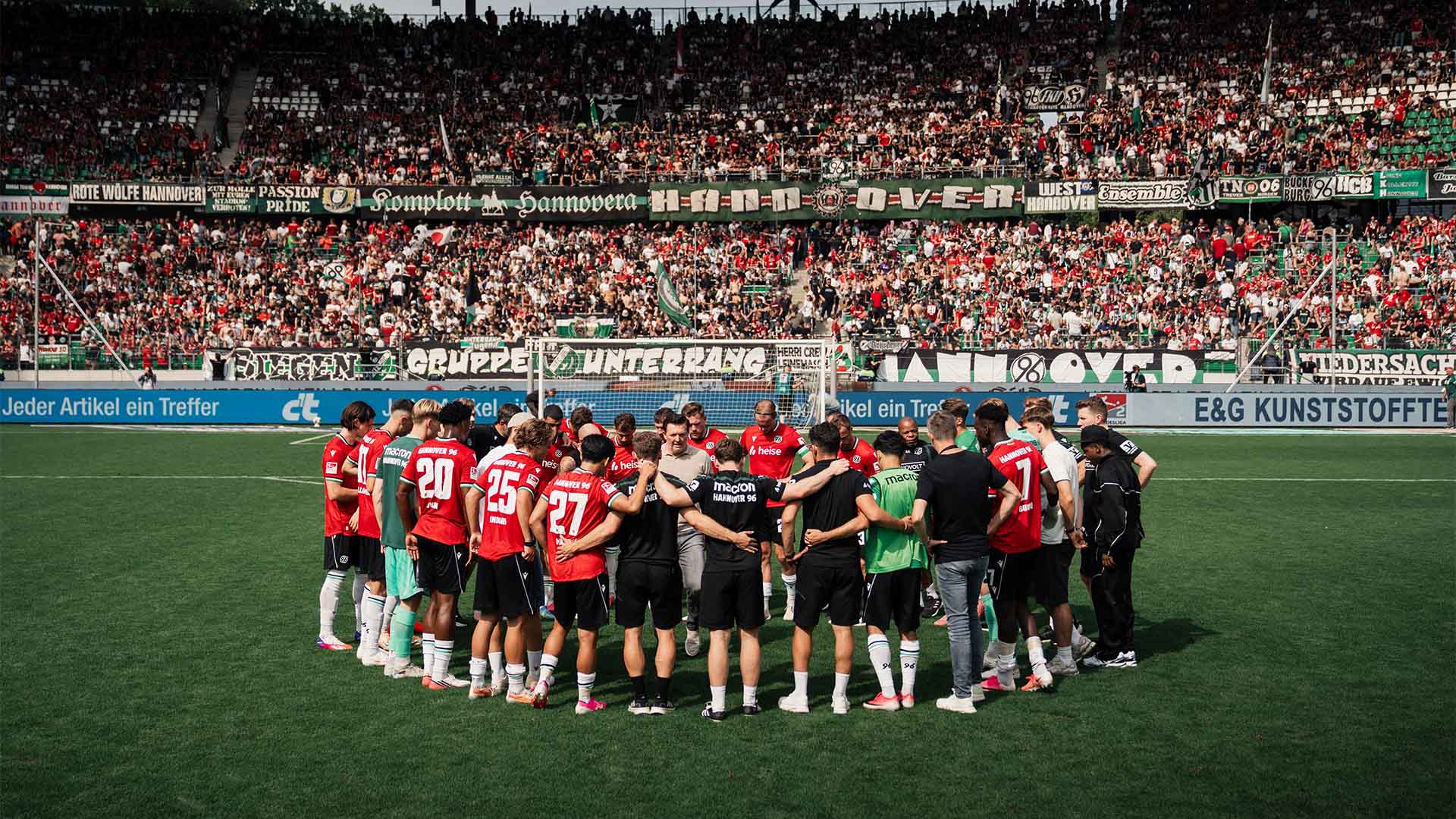 Die komplette 96-Mannschaft bildet einen Kreis vor der vollen Nordkurve im 96-Stadion.