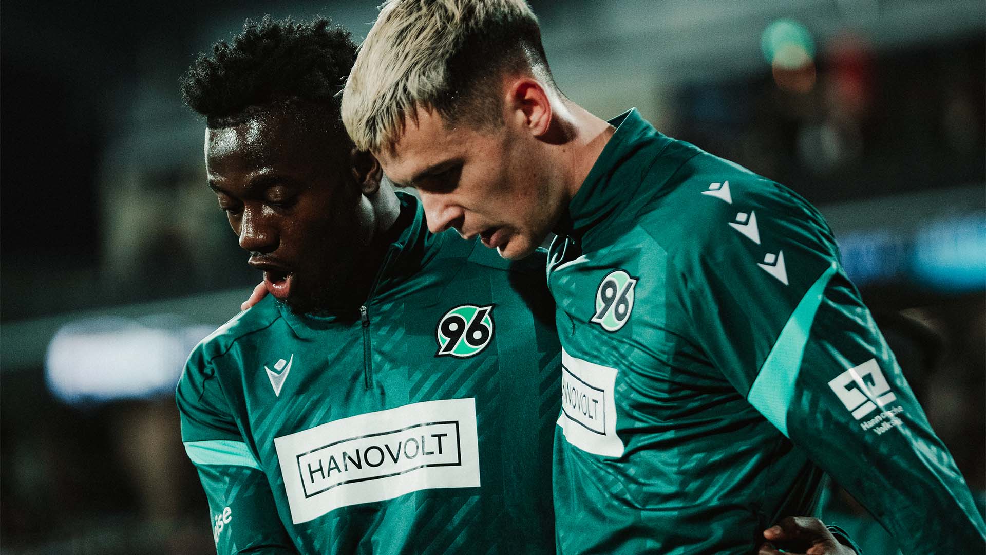 Mustapha Bundu und Bastian Allgeier laufen nach einem Spiel Arm in Arm.