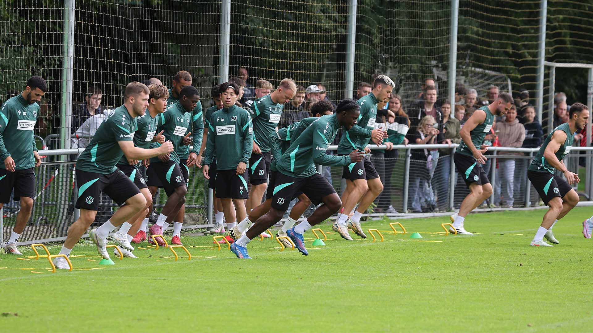 Die 96-Mannschaft absolviert ein Athletikprogramm, im Hintergrund schauen Fans zu.