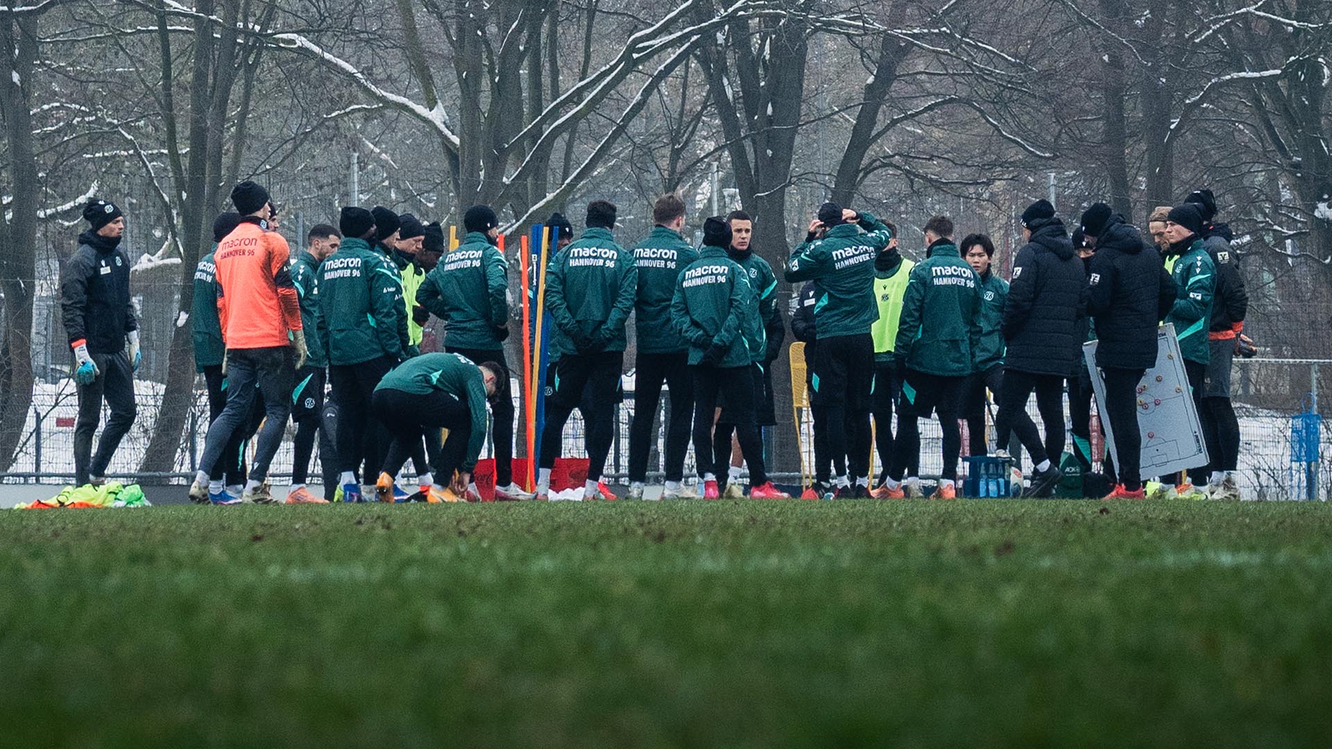 Die 96-Mannschaft steht im Kreis auf dem Trainingsplatz, alle sind dick angezogen, einige tragen Mützen.