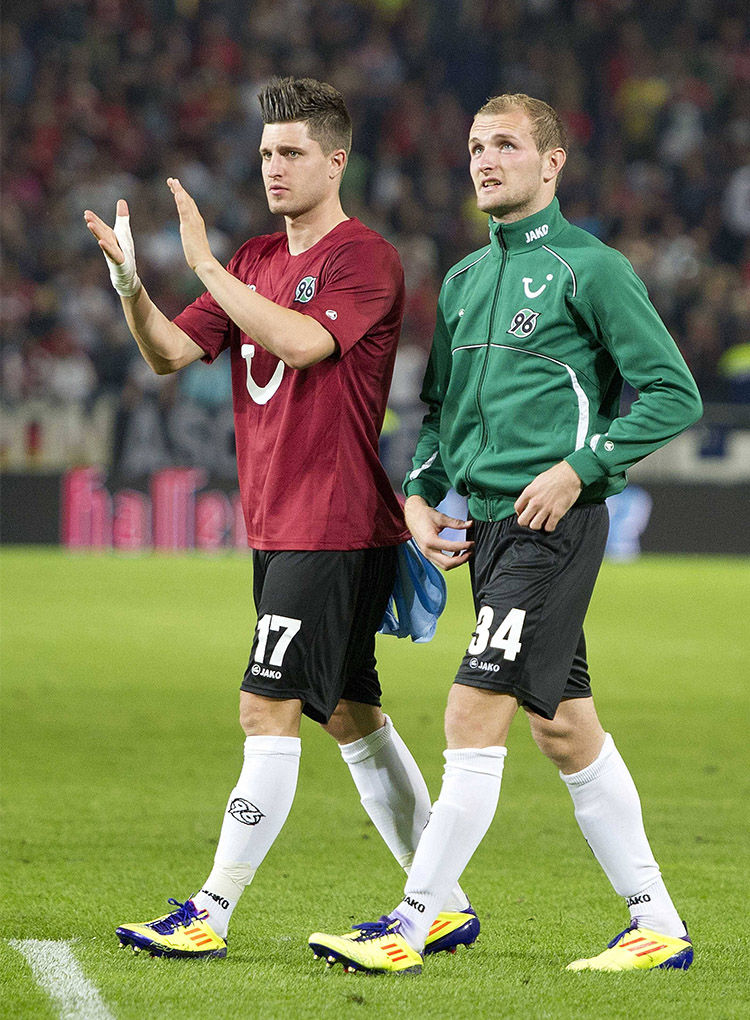 Zwei 96-Spieler drehen eine Runde auf dem Platz, einer klatscht in die Hände.