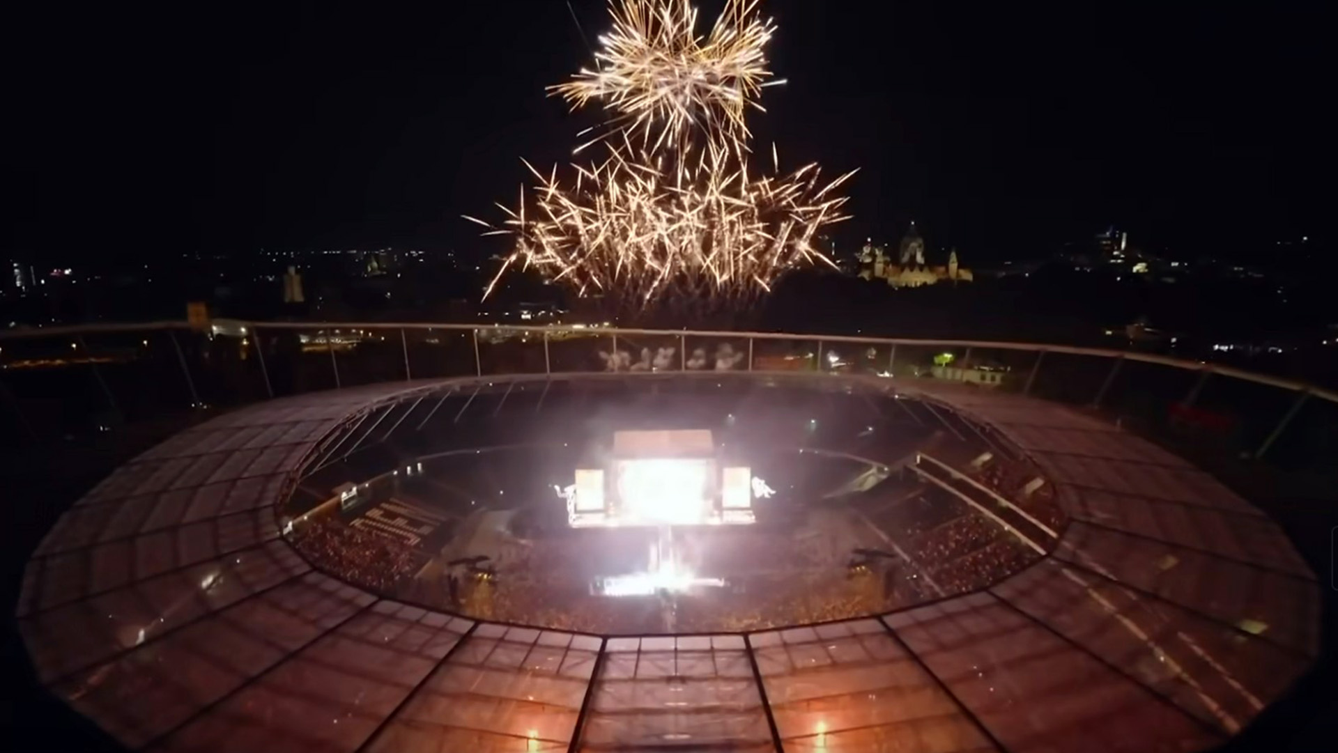 Außenaufnahme der Heinz von Heiden Arena bei Dunkelheit, innen leuchtet die Bühne, darüber ist ein Feuerwerk.