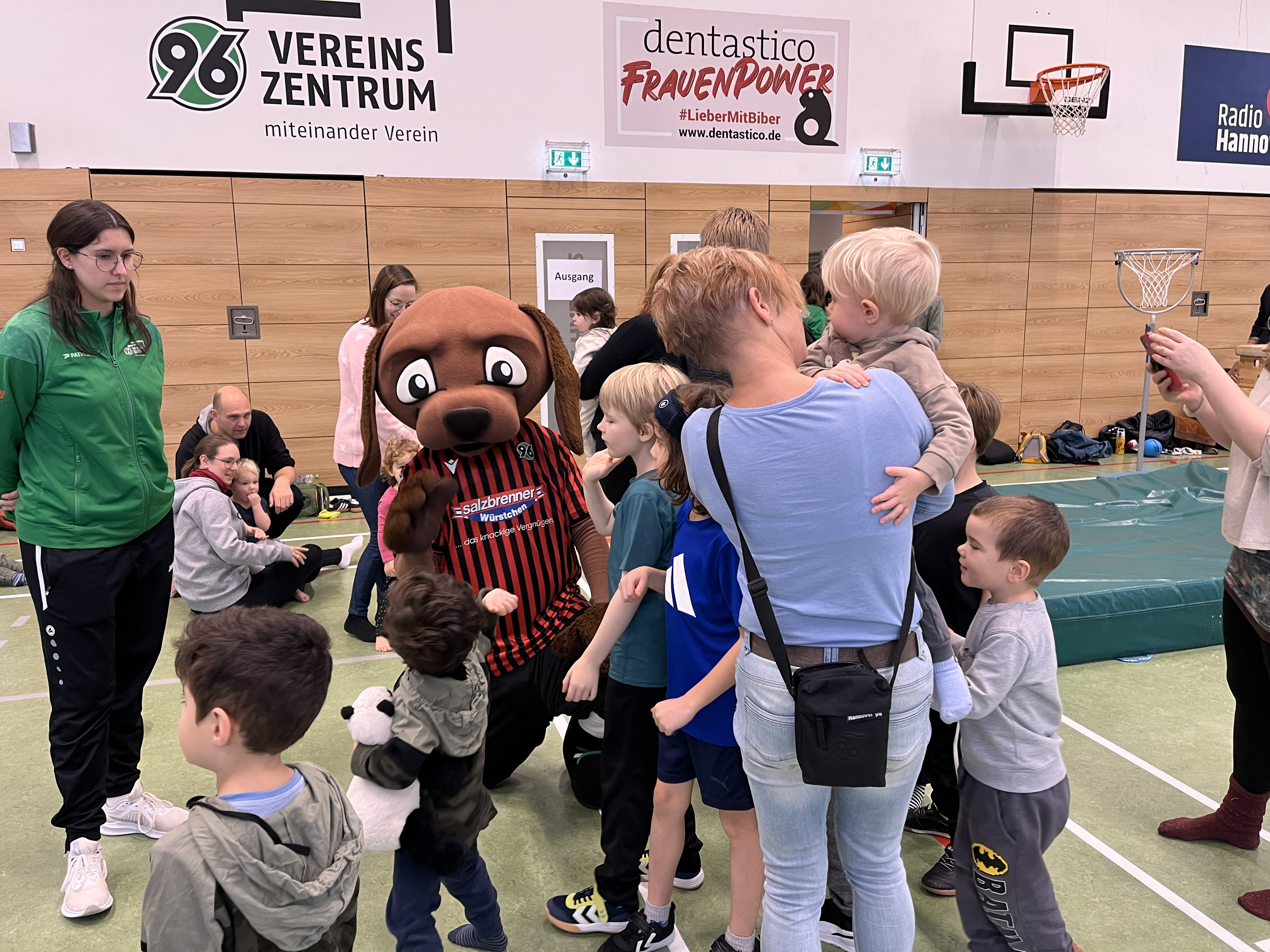 Kinder und Eltern stehen um Maskottchen EDDI.
