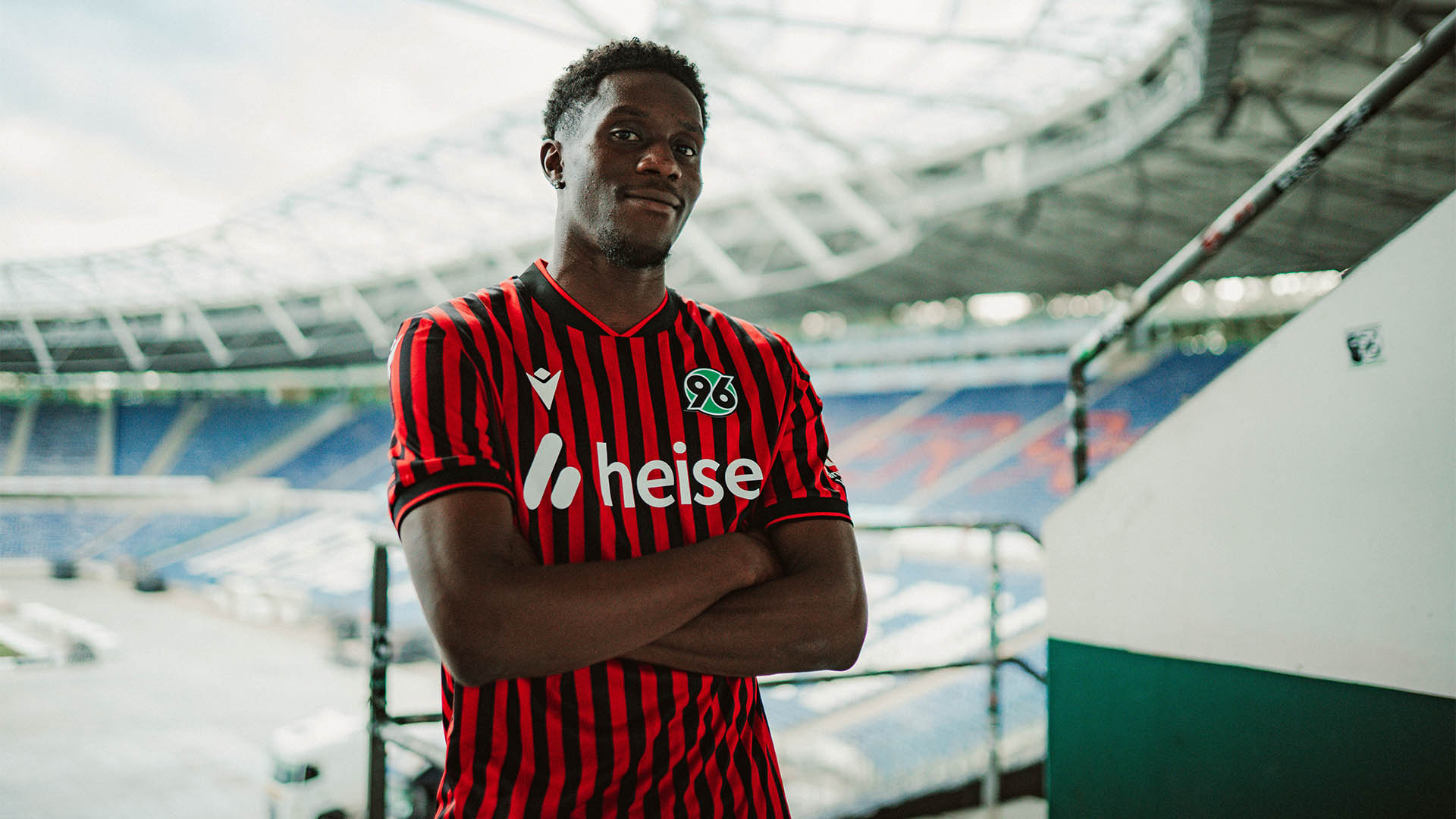 William Kokolo steht im Heimtrikot im Nordoberrang im Stadion, im Hintergrund sind unscharf die Ränge zu erkennen.