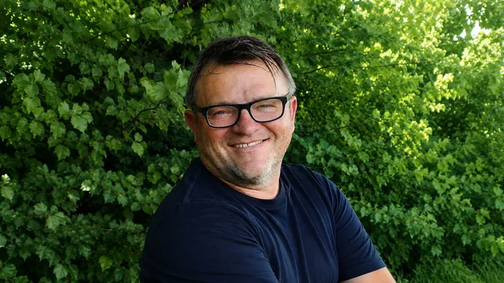 Ein Mann mit Brille lächelt freundlich in die Kamera.