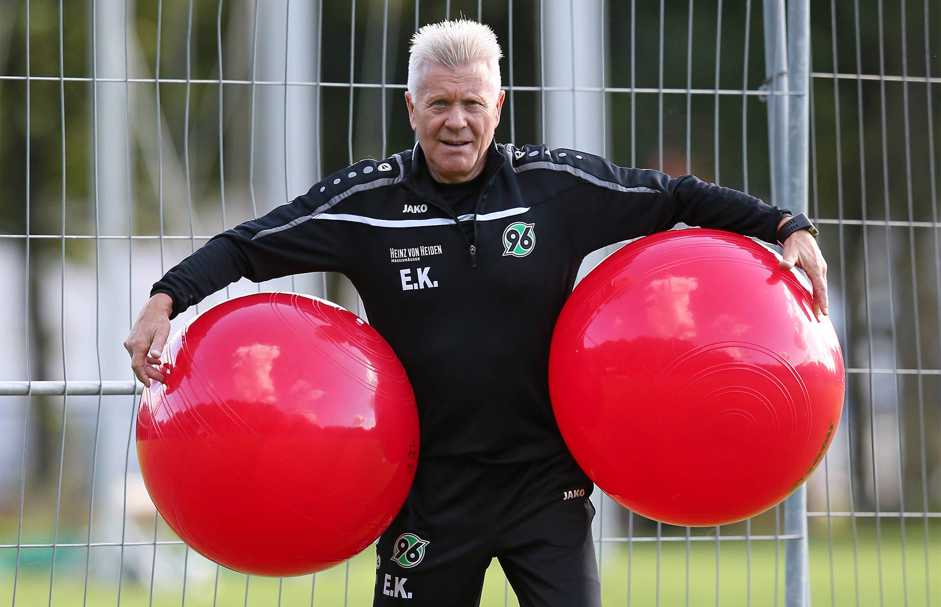 Edward Kowalczuk hält links und rechts jeweils einen großen roten Gymnastikball unter dem Arm.