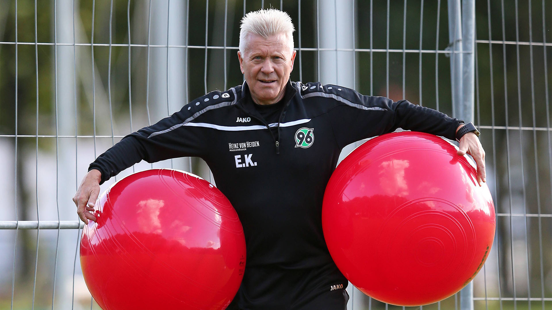Edward Kowalczuk hält links und rechts jeweils einen großen roten Gymnastikball unter dem Arm.
