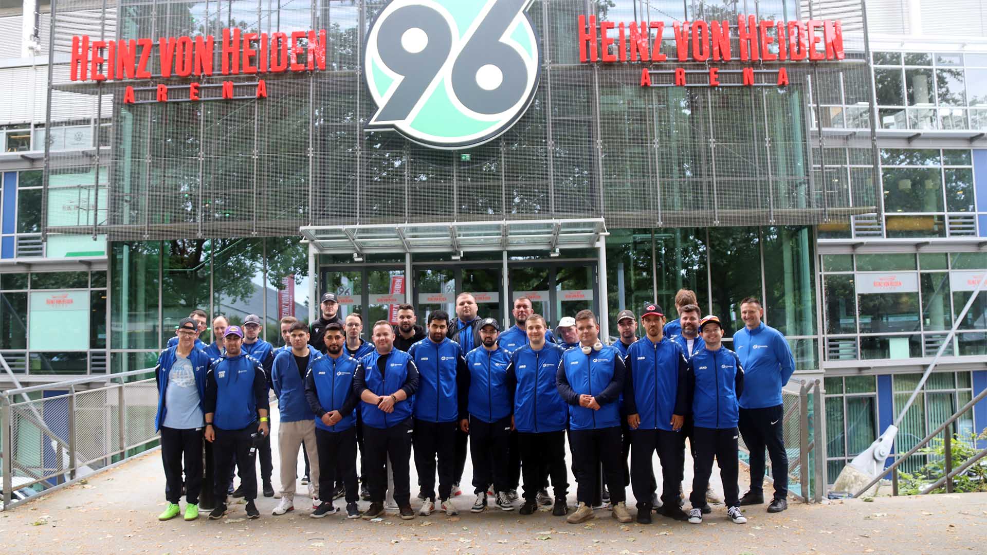 Eine Gruppe von etwas mehr als zwanzig Personen steht vor dem Osteingang der Heinz von Heiden Arena.