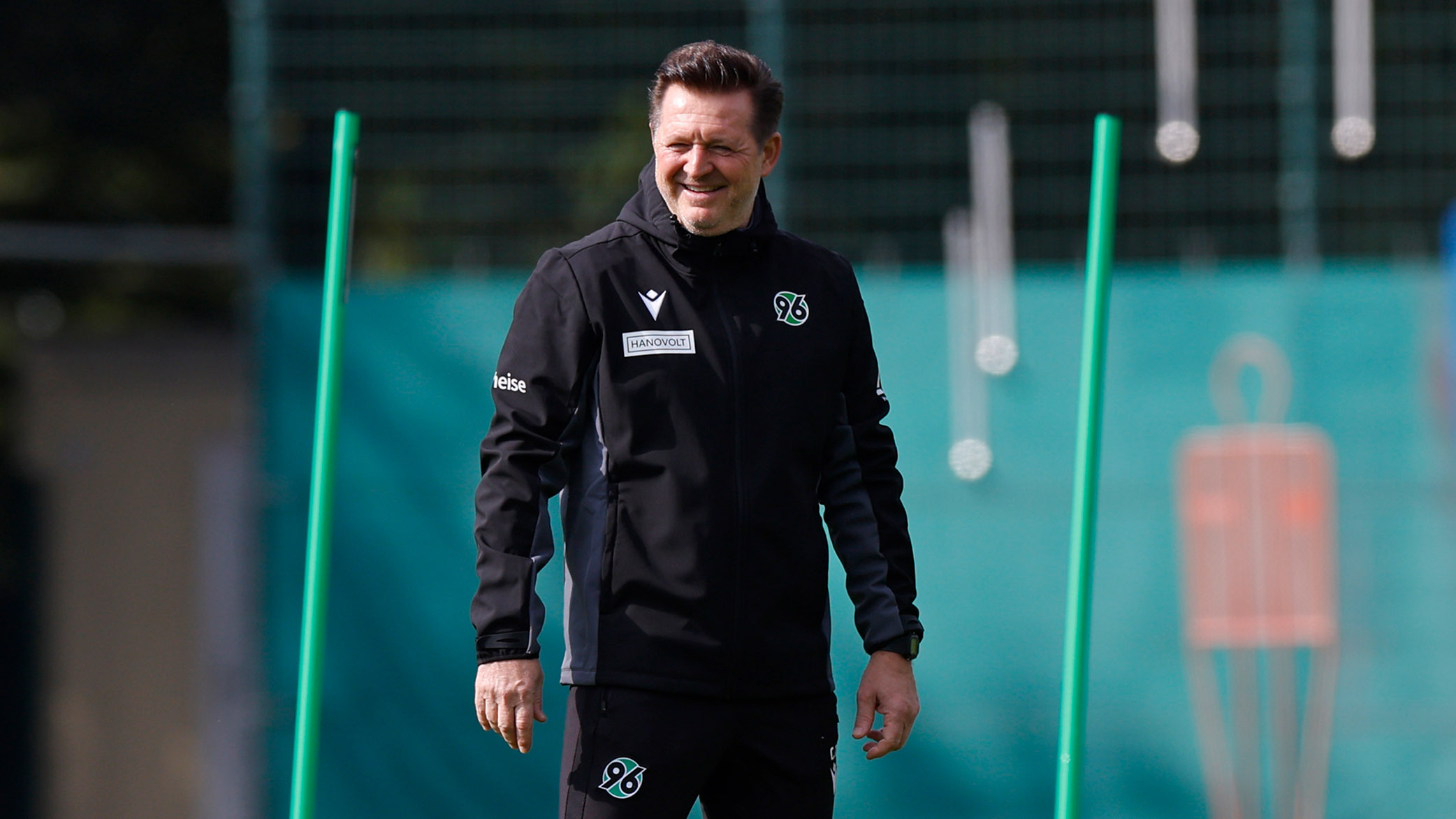 Christian Titz steht auf dem Trainingsplatz und lächelt.