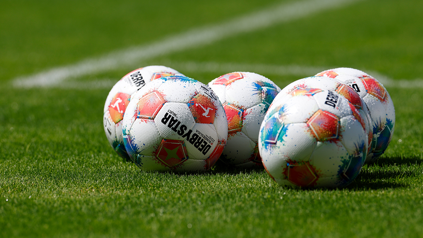 Die neuen Spielbälle der Bundesliga liegen in einem Haufen auf dem Rasen.