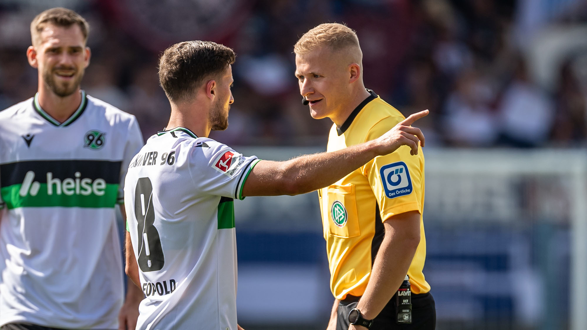 Schiedsrichter Timo Gansloweit diskutiert mit 96-Kapitän Enzo Leopold auf dem Feld.