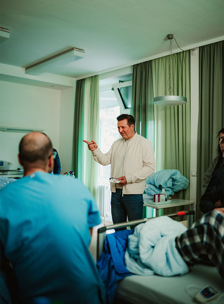 Christian Titz erzählt gestikulierend in einem Krankenhauszimmer.