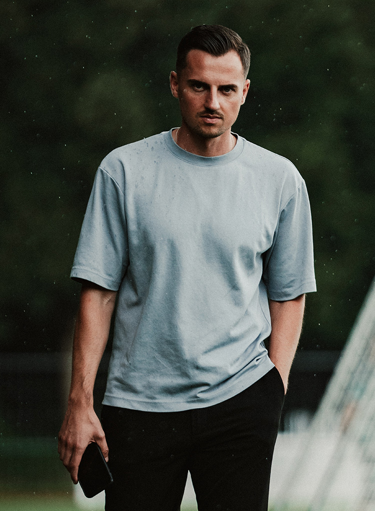 Maximilian Lüftl mit der Hand in einer Hosentasche und dem Handy in der anderen Hand.