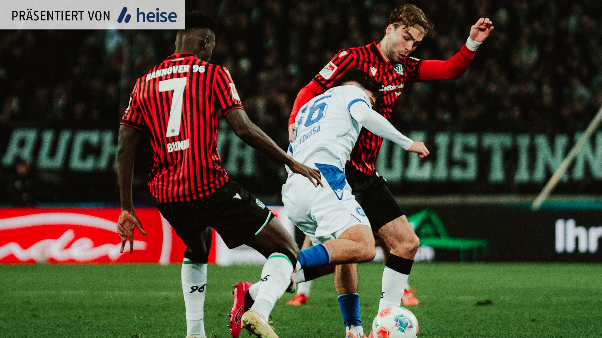 Zwei 96-Spieler im Kampf um den Ball gegen einen Karlsruhe Spieler.