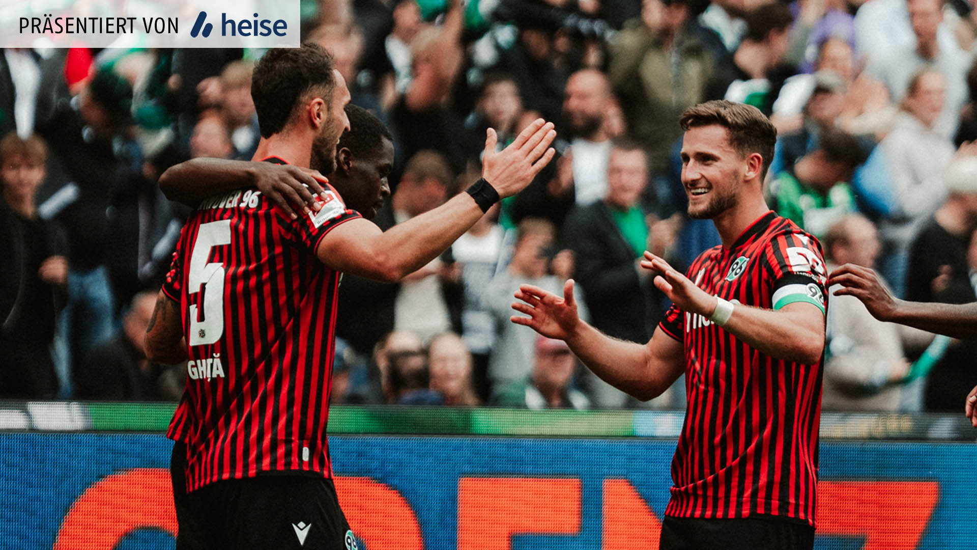 Fußballspieler klatschen sich in einem vollen Stadion ab.