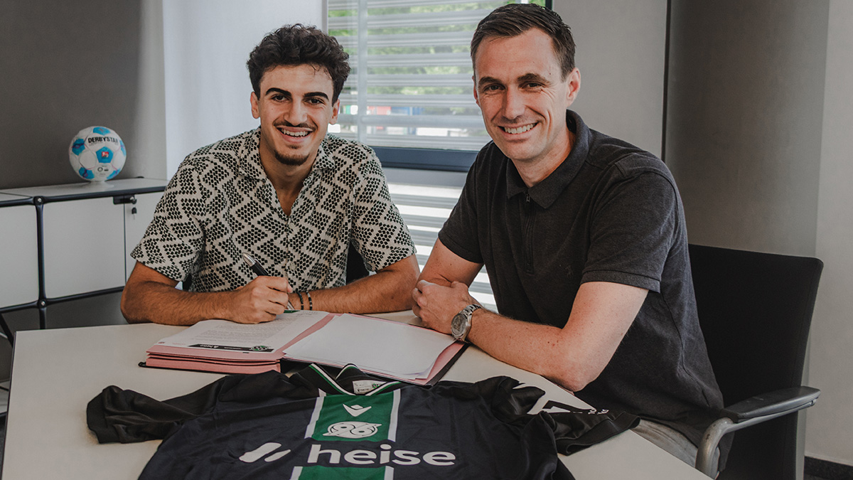 Husseyn Chakroun unterschreibt seinen Vertrag, rechts neben ihm sitzt Marcus Mann.