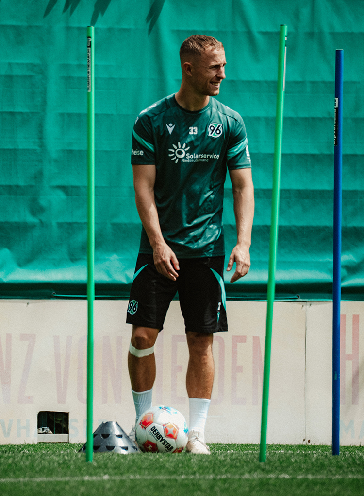 Maurice Neubauer steht im Training mit Ball am Hütchen.