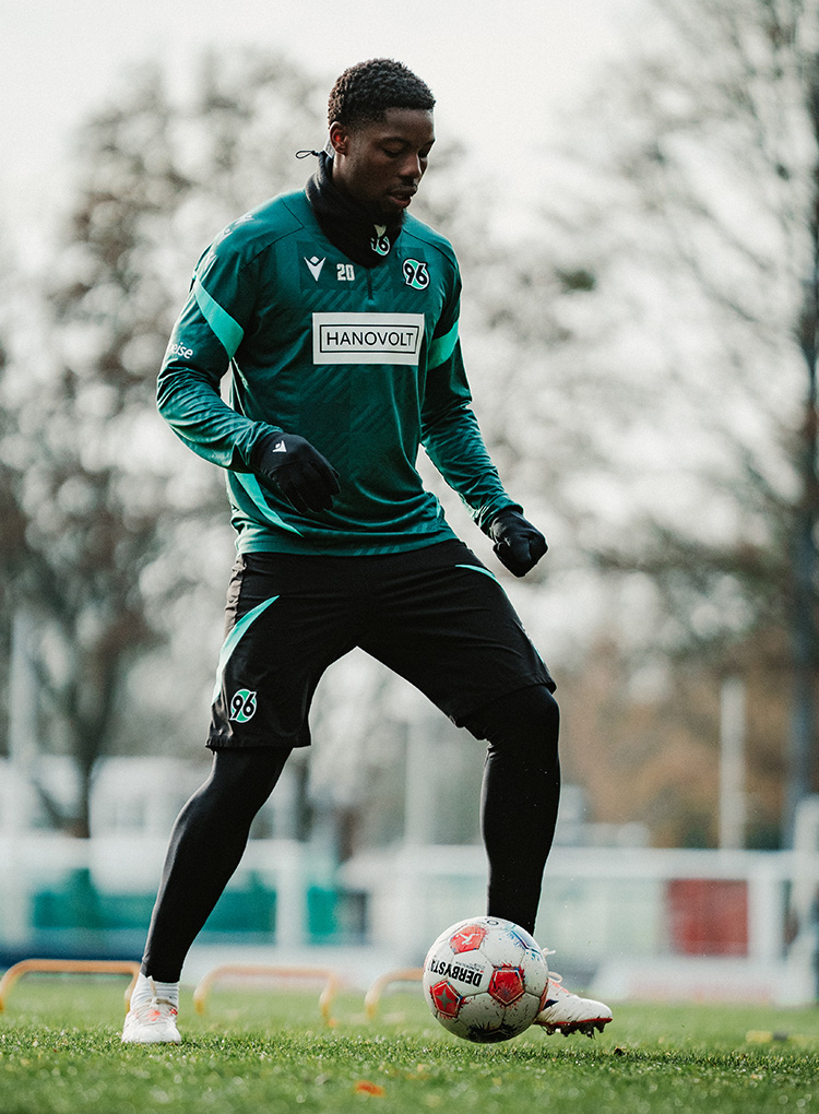Ime Okon kontrolliert im Training den Ball mit dem Fuß. Er trägt einen grünen Trainingspullover und blickt nach unten auf den Ball.