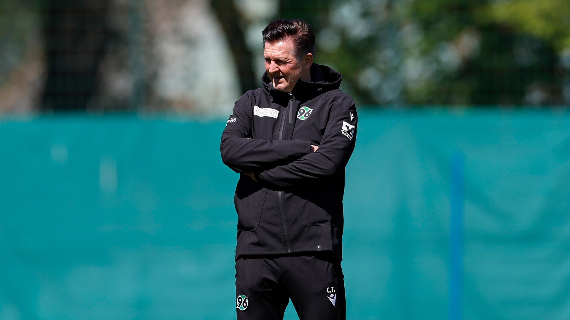 Christian Titz steht mit verschränkten Armen auf dem Trainingsplatz.
