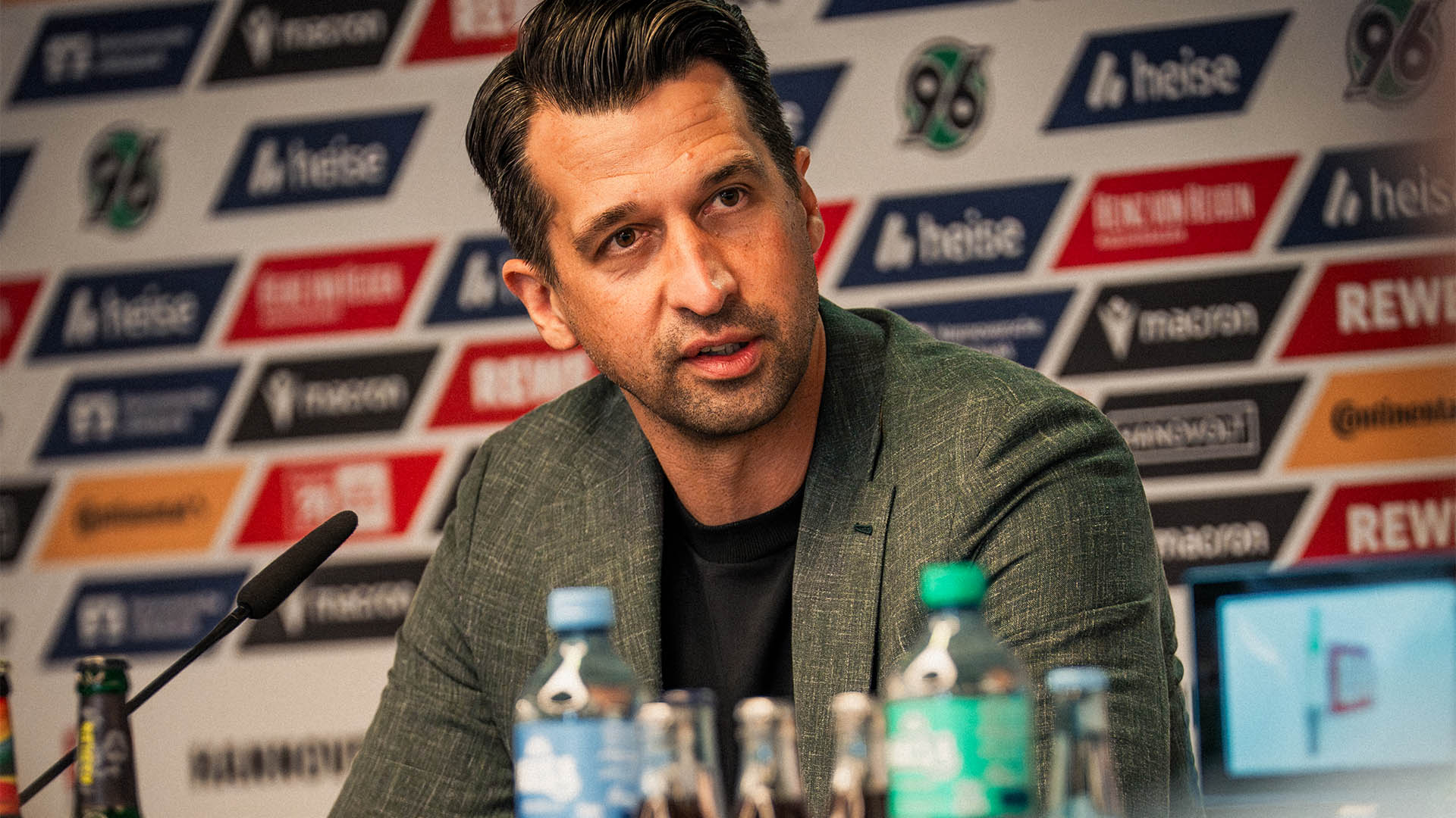 Jonas Boldt im Anzug auf dem Pressekonferenz-Podium.