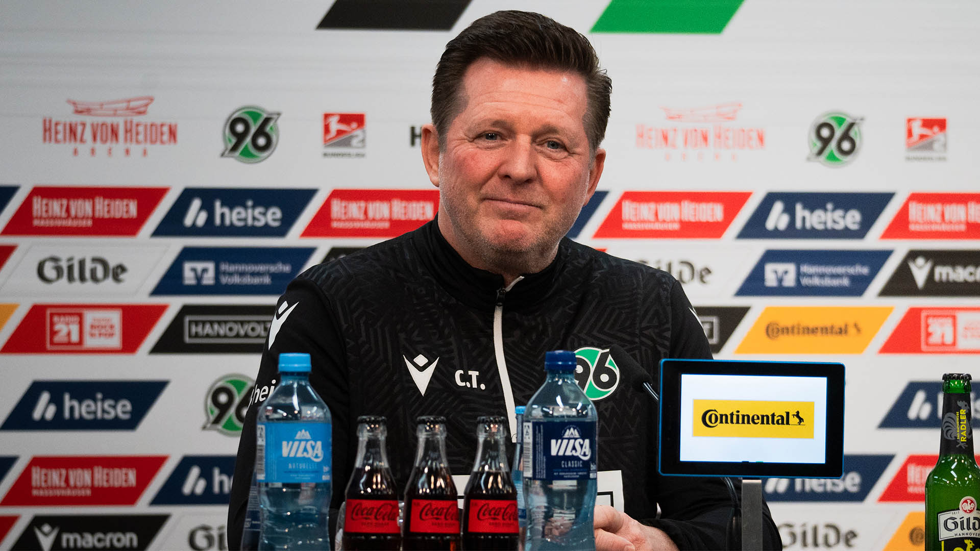 Christian Titz vor einer Sponsorenwand auf dem Pressekonferenz-Podium.